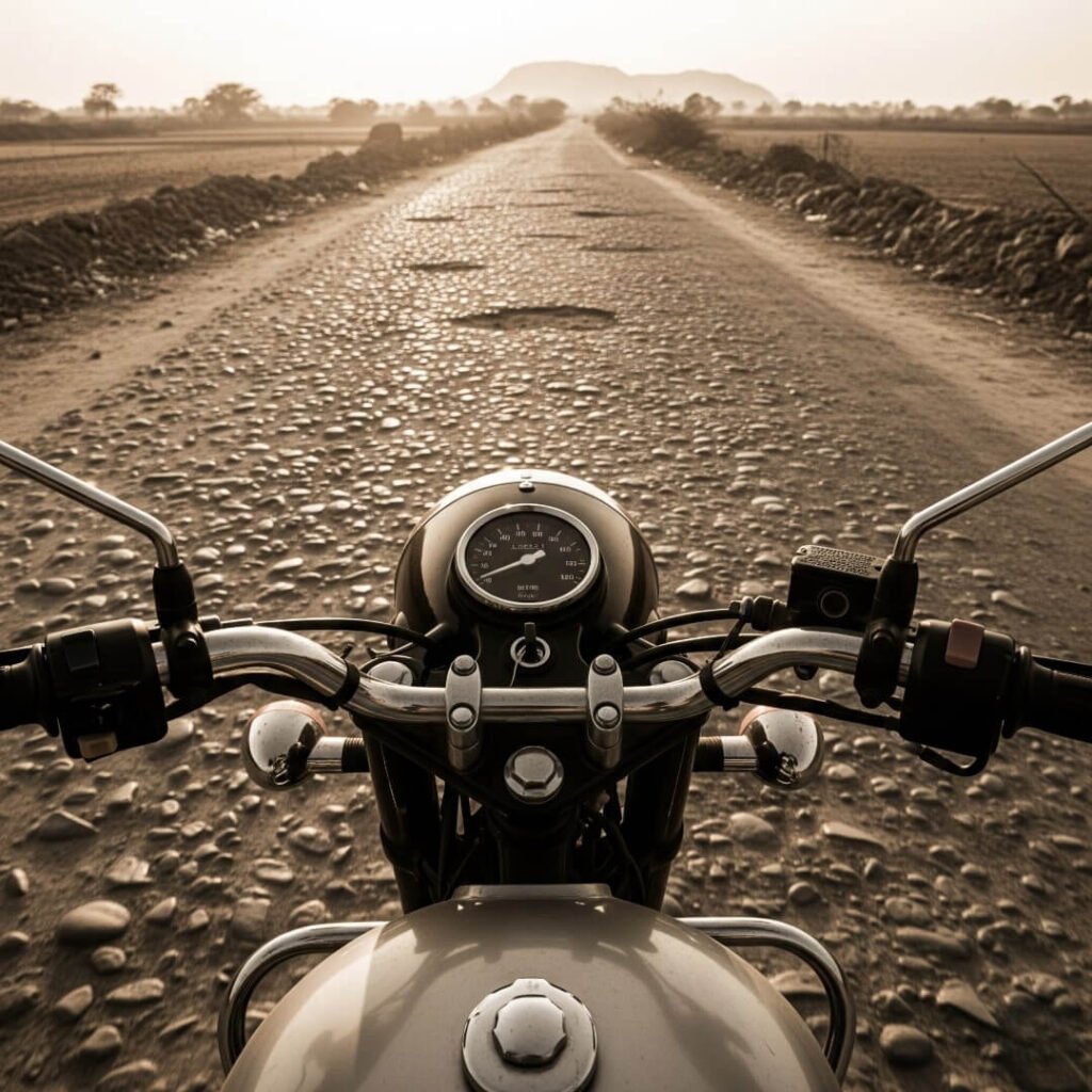 POV from motorcycle, handlebars, bumpy Indian road ahead.